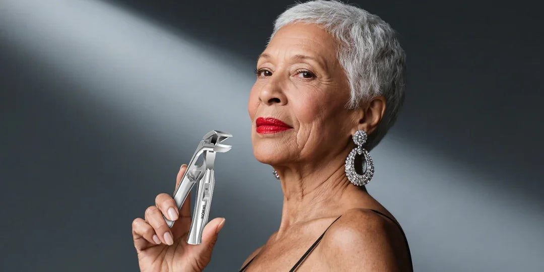 Elegant woman with short gray hair holding stainless steel nail clippers, dark background