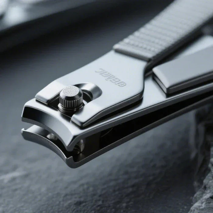 Close-up of a stainless steel nail clipper with textured handle on a dark surface